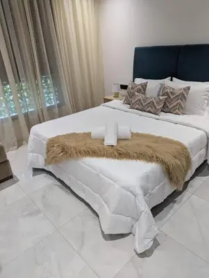 a bedroom with a large white bed with a brown blanket at Studio cosy avec patio privé -centre Rabat- Océan in Rabat