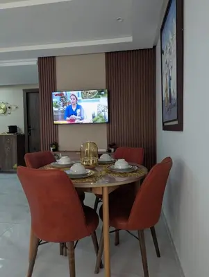a dining room table with red chairs and a tv at Studio cosy avec patio privé -centre Rabat- Océan in Rabat