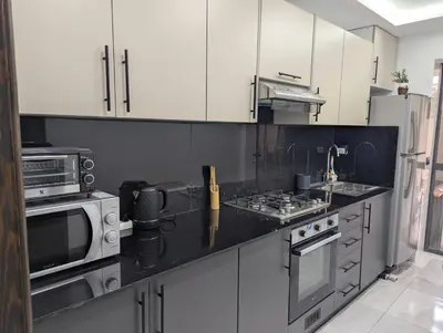 a kitchen with stainless steel appliances and white cabinets at Studio cosy avec patio privé -centre Rabat- Océan in Rabat