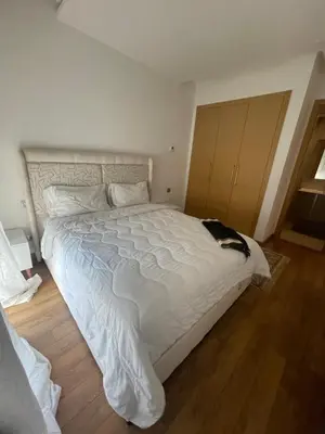 a bedroom with a large white bed and a wooden floor at appartement 5min a pied du stade in Rabat