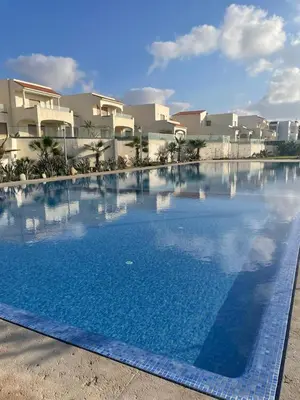a large blue swimming pool in front of some buildings at Beautiful beachfront villa in Dar Bouazza