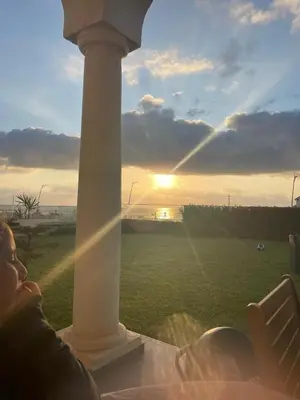 a person sitting on a porch watching the sunset at Beautiful beachfront villa in Dar Bouazza