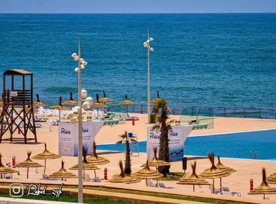 a beach with a lot of umbrellas and the ocean at Luxury SeaView Apartment 2 Minutes From Beachfront in Rabat