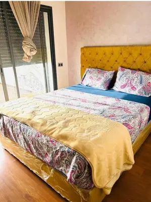 a bedroom with a bed with a yellow bedspread and pillows at residence cheickno firdaous casablanca in Settat