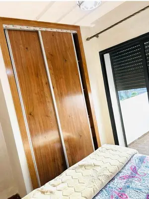 a bedroom with a bed and a wooden closet at residence cheickno firdaous casablanca in Settat