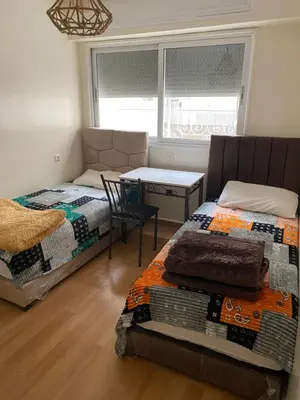 a bedroom with two beds and a desk and a chair at Casablanca Happy Homestay in Casablanca