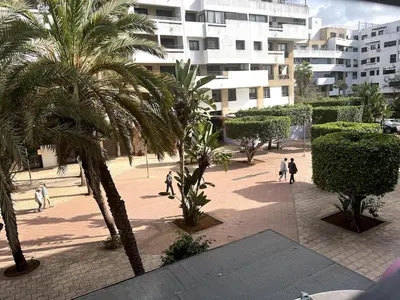 people walking in a park with palm trees and buildings at Beautiful 3 Bedroom in Heart of Hay Riad in Rabat