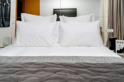 a bed with white sheets and pillows on it at Appartement cosy & chic Triangle d'or in Casablanca