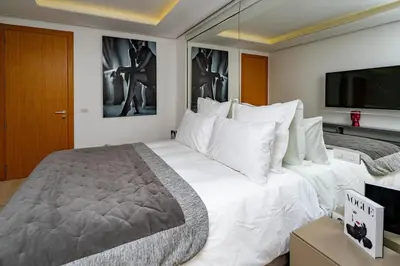 a bedroom with a large white bed with a flat screen tv at Appartement cosy & chic Triangle d'or in Casablanca