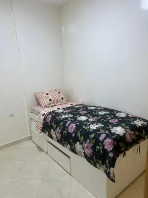 a small bed with a black and pink blanket on it at Appartement in Mohammedia