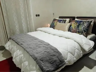 a large white bed with pillows on top of it at Studio confortable au centre rabat agdal à côté du stade in Gare de Rabat-Aguedal