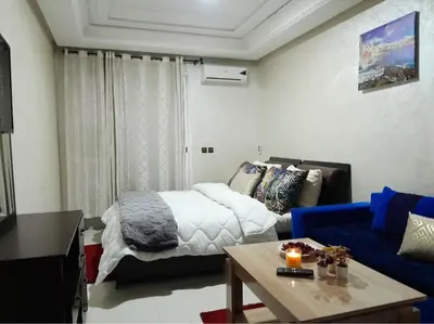 a living room with a bed and a blue couch at Studio confortable au centre rabat agdal à côté du stade in Gare de Rabat-Aguedal
