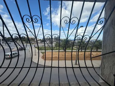 a gate with a view of a road through a fence at Appartement à 2 min gare Agdal bien situé in Rabat