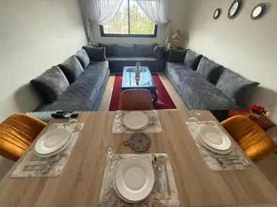 a living room with a long couch and a table at Appartement à 2 min gare Agdal bien situé in Rabat