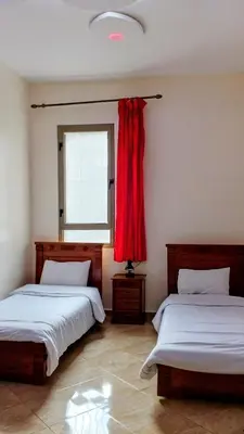 a bedroom with two beds and a window with a red curtain at Casablanca City Center Neoclassic Flat in Casablanca