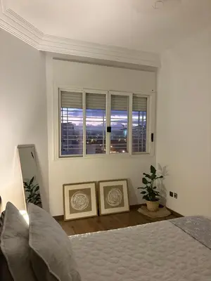 a white bedroom with a bed and a window at The green stay in Rabat