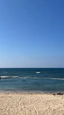 a beach with the ocean and some people in the water at Spacious beach escape villa with pool & play areas in Mansouria
