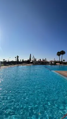 a large pool of blue water next to a beach at Spacious beach escape villa with pool & play areas in Mansouria