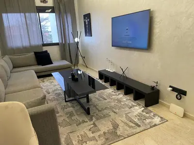 a living room with a couch and a tv on the wall at Studio oasis calme et spacieux in Maarif