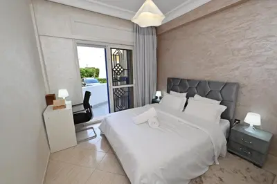 a bedroom with a large white bed and a chair at Modern Luxury Apartment - Ground Floor in Rabat