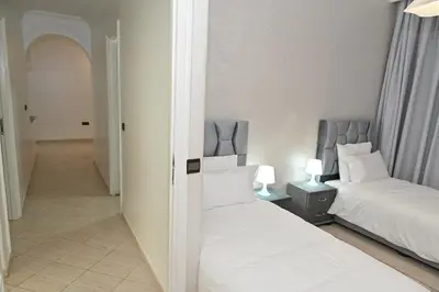 a bedroom with two beds and a hallway at Modern Luxury Apartment - Ground Floor in Rabat