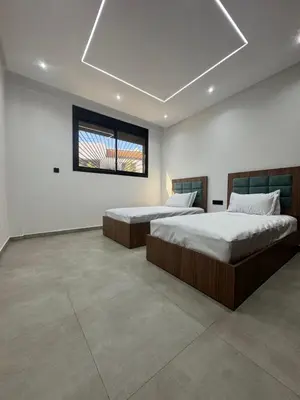two beds in a large room with a window at Appartement sur villa in Temara