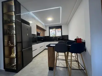 a kitchen with a black refrigerator and two bar stools at Appartement sur villa in Temara
