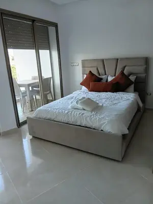 a bedroom with a large bed with a balcony at Palm Pool View Apartment - Bouznika in Bouznika