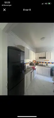 a kitchen with white cabinets and a black refrigerator at Amir 11 A in Casablanca