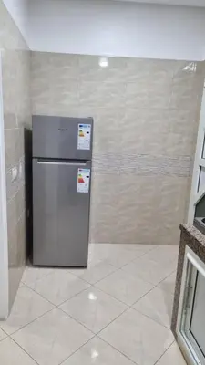 a refrigerator in a room with a tile wall at Appartement moderne Temara à 10 minutes de Rabat in Temara