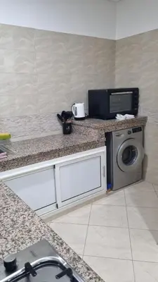 a kitchen with a washing machine and a microwave at Appartement moderne Temara à 10 minutes de Rabat in Temara