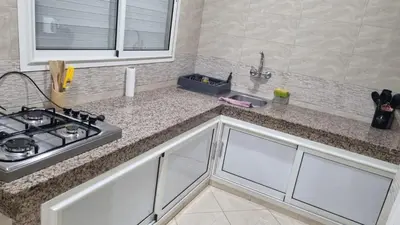 a kitchen counter with a sink and a stove at Appartement moderne Temara à 10 minutes de Rabat in Temara