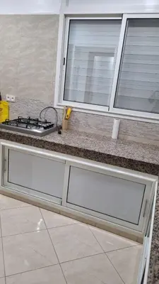 a kitchen counter with two windows and a stove at Appartement moderne Temara à 10 minutes de Rabat in Temara