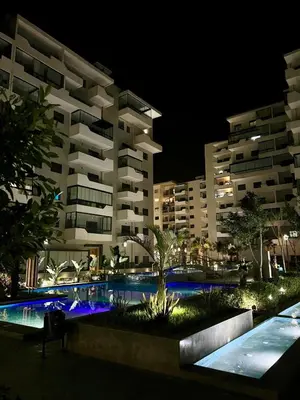 a large apartment building with a swimming pool at night at Appart luxeux à zenata piscine , plage à 3 min in Aïn Harrouda