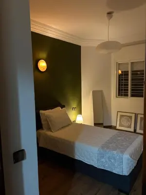 a bedroom with a bed and a green wall at The Green homestay in Rabat