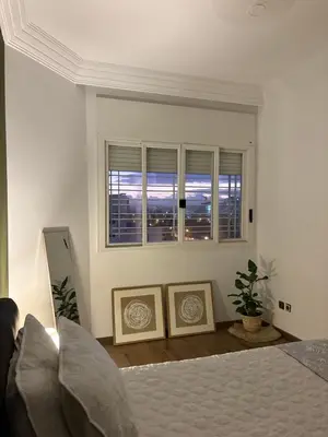 a white bedroom with a bed and a window at The Green homestay in Rabat