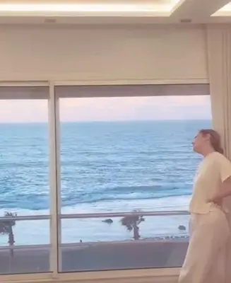 a woman looking out a window at the ocean at Apartment with impressive sea view! in Rabat