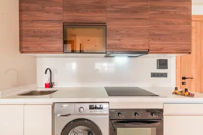 a kitchen with a washing machine and wooden cabinets at L'osmo - 1 BR - 2m from CFC in Casablanca