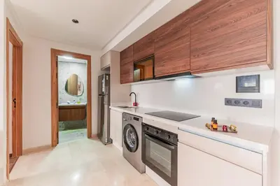 a kitchen with white counters and wooden cabinets at L'osmo - 1 BR - 2m from CFC in Casablanca