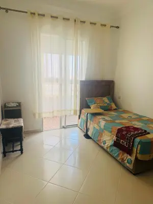a bedroom with a bed and a large window at Appartement lumineux a belvedere in Casablanca