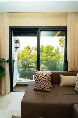a living room with a couch and a large window at Suite Cosy Moderne Chic Calme Jardin and Habous in Casablanca