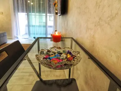 a candle on a glass table with a bowl of candy at Appart de luxe, Confort et Emplacement, Corniche STAY MEMORIES in Mohammedia