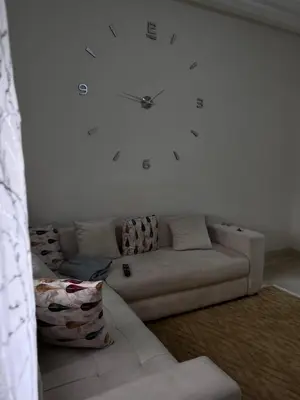 a white couch in a living room with a clock on the wall at Appartement journalier in Rabat