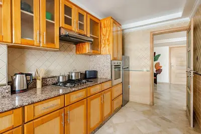 a kitchen with wooden cabinets and a stove at Spacious, 2 BDR, Balcony, AC, Parking, Fiber Optic - Agdal in Rabat