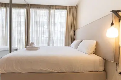a bedroom with a large white bed with windows at B-living Luxury studio Maarif palmier in Casablanca