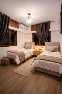 two beds in a room with two windows at Spacious 3 Bedroom Apartment in Rabat Near Moulay El Hassan Stadium Malls and Embassies in Rabat