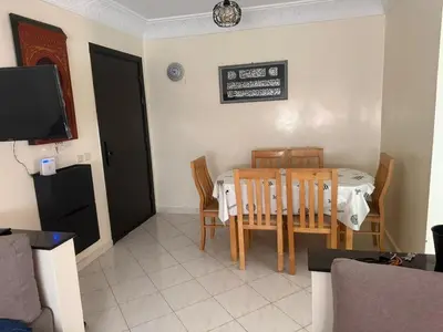 a dining room with a table and chairs and a television at Appart Tamaris DARB in Dar Bouazza