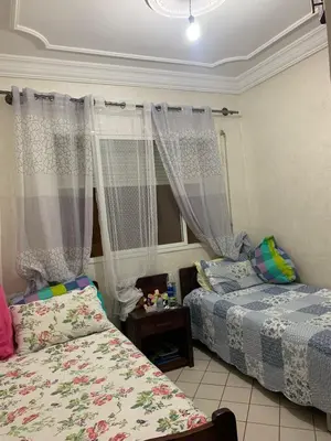 a bedroom with two beds and a window with curtains at Halimadriss in Rabat