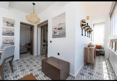 a living room with a table and a chair at Appartement Cosy avec Vue Piscine in Mansouria