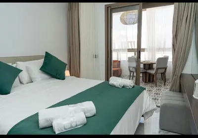 a bedroom with a bed with green and white sheets at Appartement Cosy avec Vue Piscine in Mansouria